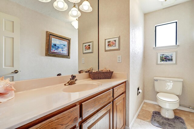 bathroom with toilet, vanity, a textured ceiling, tile patterned flooring, and baseboards