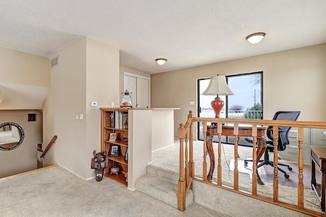 stairs with a textured ceiling, carpet flooring, visible vents, and baseboards