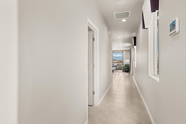 corridor with light tile patterned floors, recessed lighting, visible vents, and baseboards