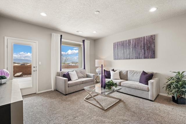 living room featuring carpet floors, baseboards, and a textured ceiling