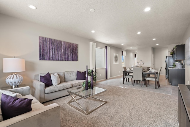 living area featuring recessed lighting, light colored carpet, a textured ceiling, and baseboards