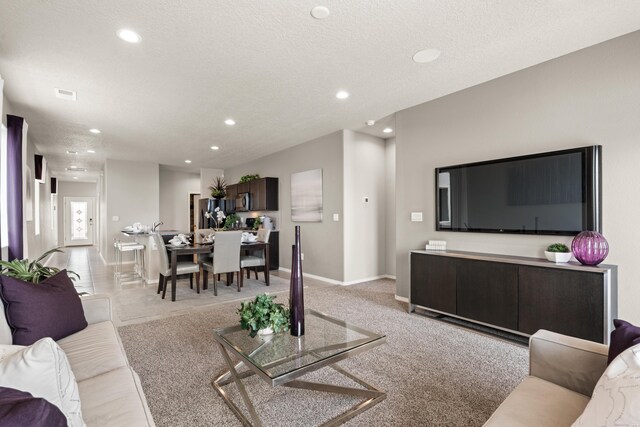 living room with baseboards, light colored carpet, a textured ceiling, and recessed lighting