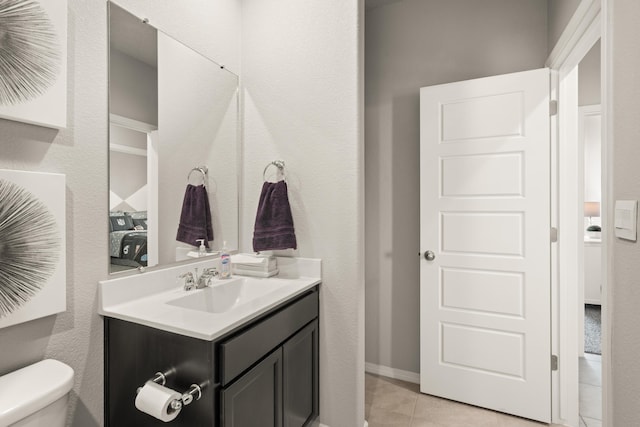 half bath with toilet, vanity, and tile patterned floors