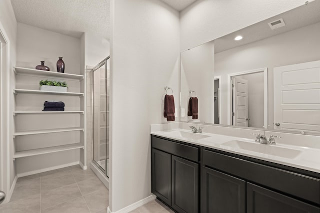 bathroom with a stall shower, a sink, and tile patterned floors