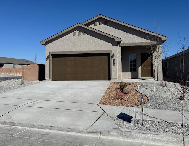 view of front of home with a garage, driveway, fence, and stucco siding