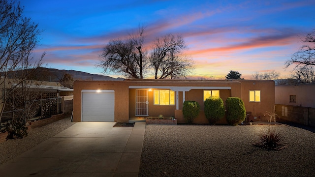 view of front facade featuring a garage, driveway, fence, and stucco siding