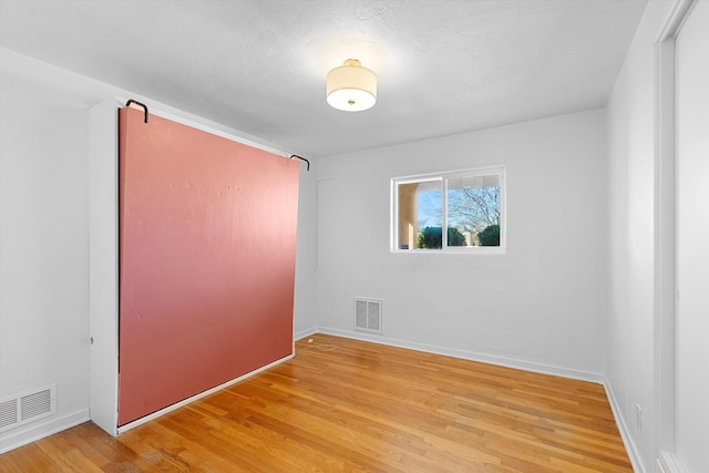 unfurnished room with baseboards, visible vents, and light wood finished floors