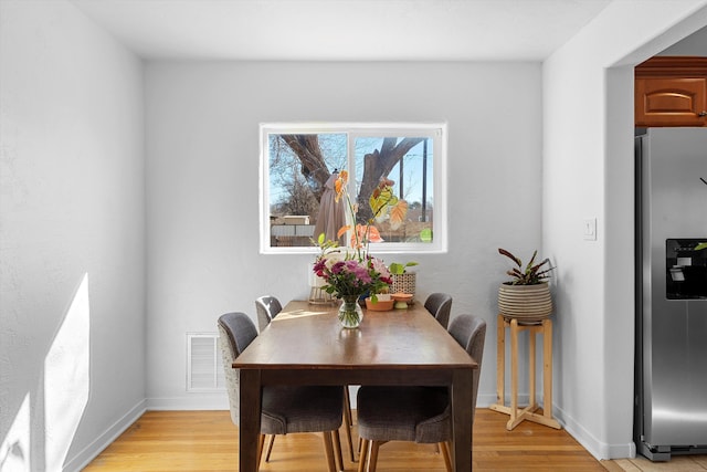 dining room featuring light wood-type flooring, visible vents, and baseboards