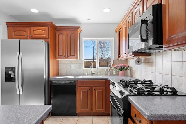 kitchen with light tile patterned floors, a sink, brown cabinets, black appliances, and tasteful backsplash