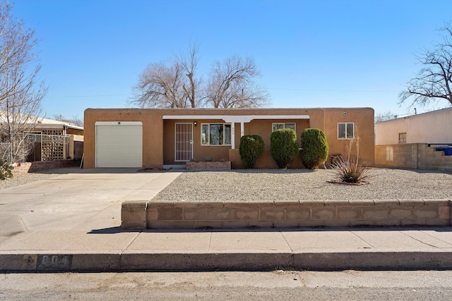 view of front of property featuring concrete driveway, fence, an attached garage, and stucco siding