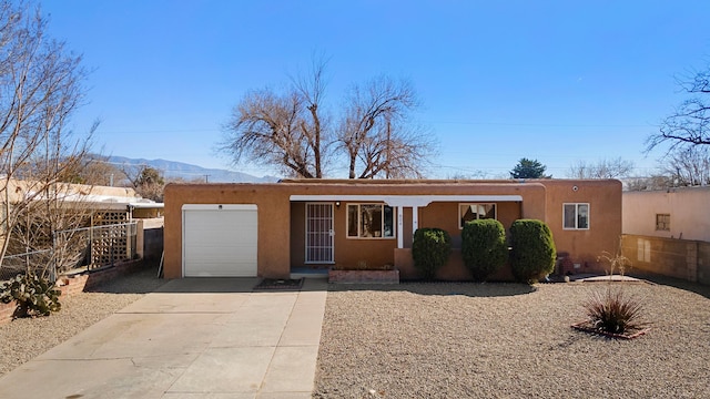 view of front of house with driveway, an attached garage, a mountain view, and stucco siding