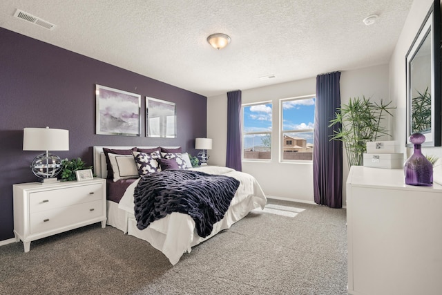 bedroom with carpet floors, visible vents, a textured ceiling, and baseboards