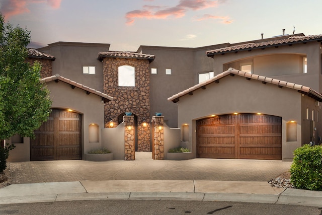 mediterranean / spanish house with decorative driveway, an attached garage, and stucco siding