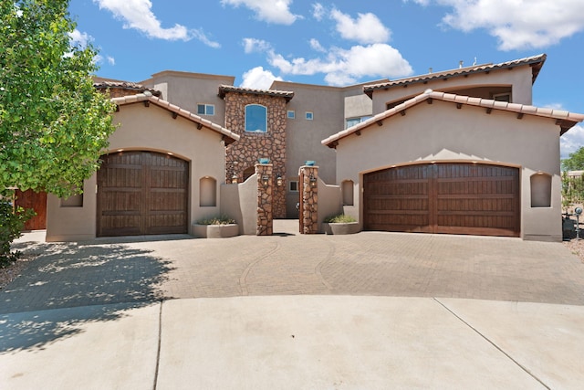 mediterranean / spanish-style house featuring a garage, decorative driveway, and stucco siding