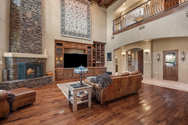 living area featuring arched walkways, visible vents, a fireplace, and wood finished floors