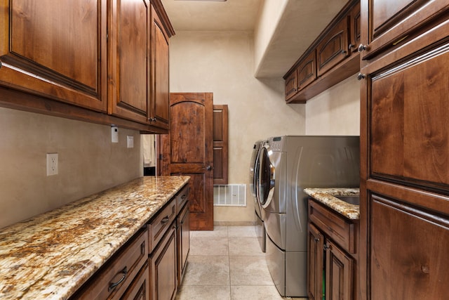 laundry room with cabinet space, light tile patterned floors, visible vents, and washing machine and clothes dryer