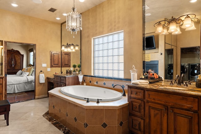 ensuite bathroom with washer and clothes dryer, ensuite bathroom, a sink, a lit fireplace, and tile patterned floors