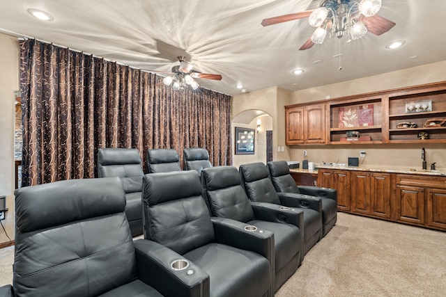 cinema room featuring arched walkways, a ceiling fan, light colored carpet, a sink, and recessed lighting