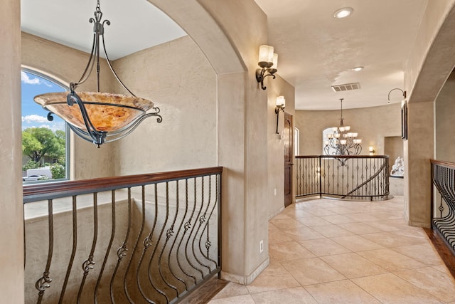 hallway featuring arched walkways, visible vents, light tile patterned flooring, an upstairs landing, and a chandelier