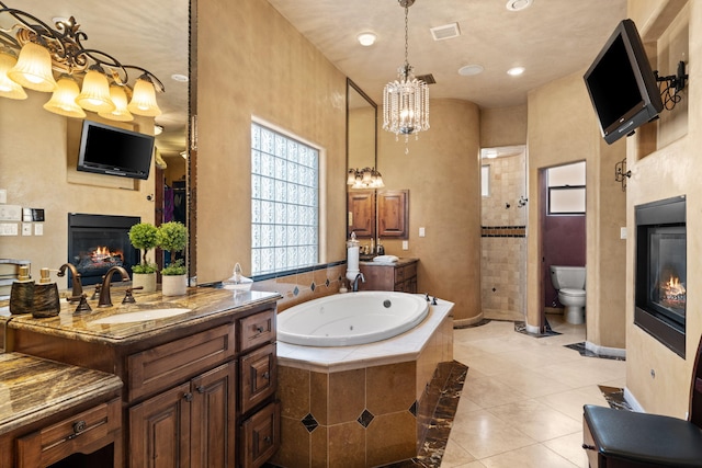 full bath featuring toilet, a notable chandelier, visible vents, tile patterned floors, and a glass covered fireplace