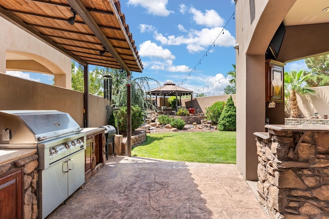 view of patio / terrace with grilling area, fence, an outdoor kitchen, and a gazebo