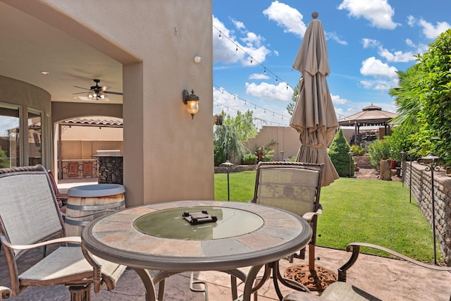 view of patio featuring a fenced backyard, ceiling fan, a gazebo, and exterior bar