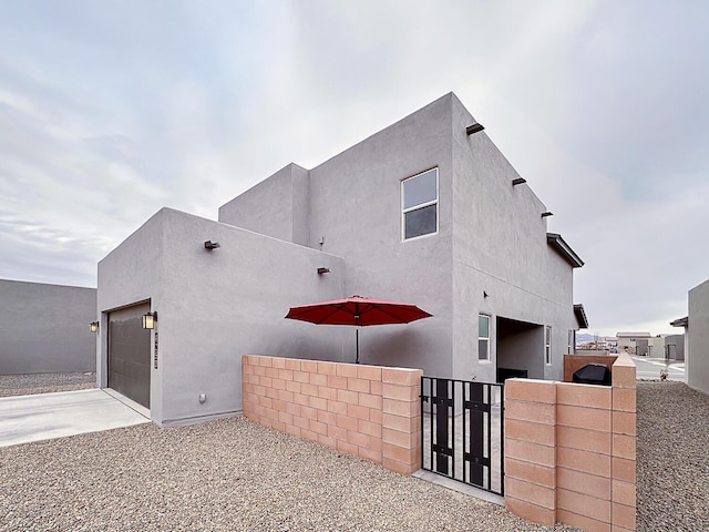 6053 Strand Loop SE, Albuquerque, NM 87106 - view of property exterior with a gate, an attached garage, concrete driveway, and stucco siding