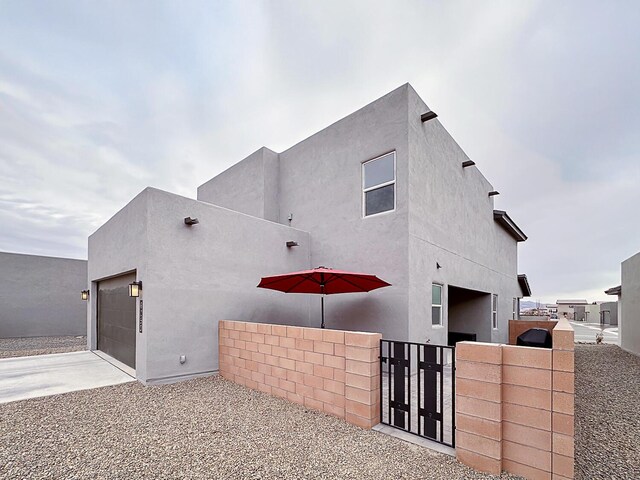6053 Strand Loop SE, Albuquerque, NM 87106 - view of property exterior with a gate, an attached garage, concrete driveway, and stucco siding