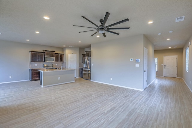 kitchen with tasteful backsplash, a center island with sink, visible vents, open floor plan, and stainless steel appliances