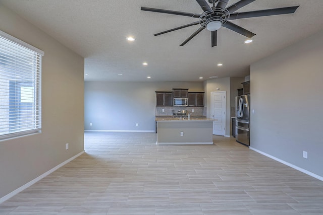 unfurnished living room featuring a textured ceiling, baseboards, and a ceiling fan