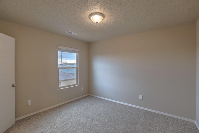 spare room featuring baseboards, a textured ceiling, visible vents, and carpet flooring