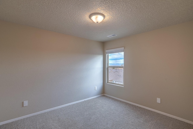 carpeted spare room featuring baseboards, visible vents, and a textured ceiling