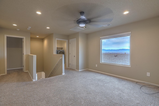 spare room with light carpet, ceiling fan, visible vents, and a textured ceiling