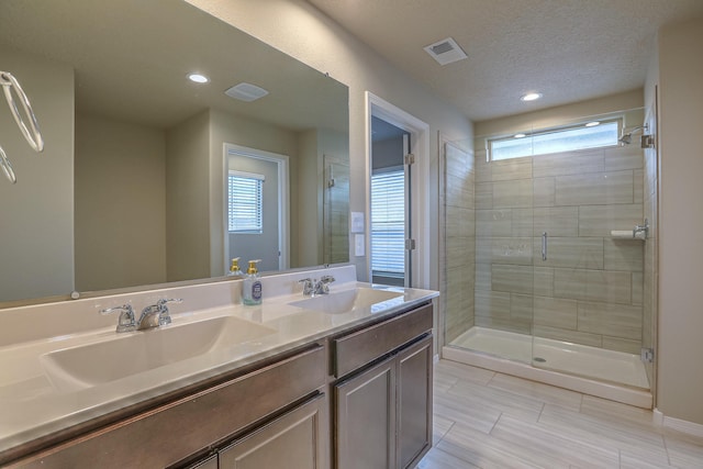 full bath with double vanity, a stall shower, a sink, and visible vents