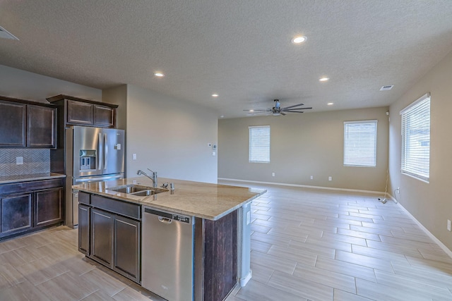 kitchen with dark brown cabinetry, a center island with sink, stainless steel appliances, and a sink