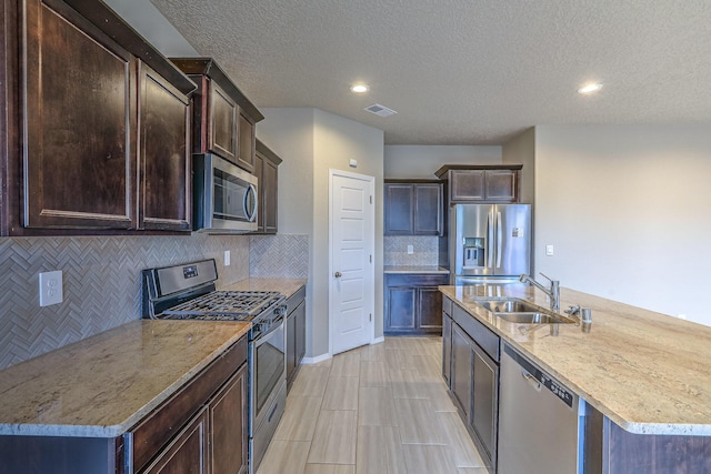 kitchen with an island with sink, visible vents, stainless steel appliances, and a sink