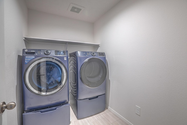 laundry area with laundry area, washing machine and dryer, visible vents, and baseboards