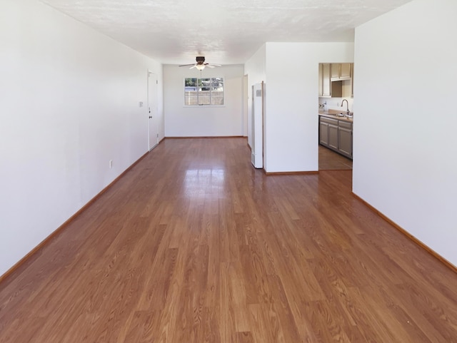 unfurnished room featuring a sink, ceiling fan, dark wood finished floors, and baseboards