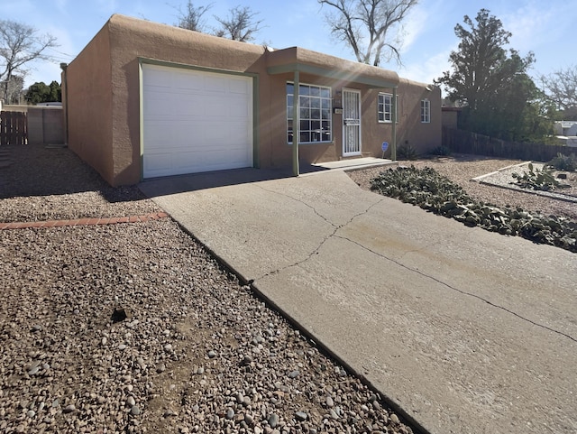 view of front of property with driveway, fence, an attached garage, and stucco siding