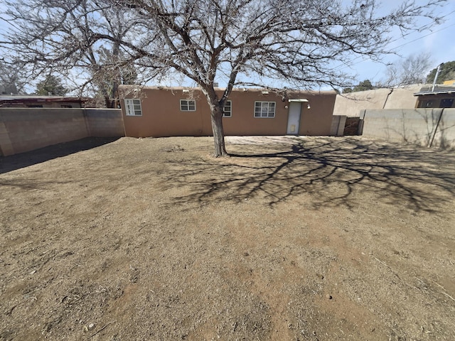 rear view of house with a fenced backyard and stucco siding