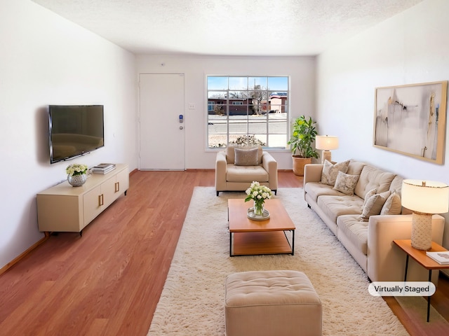 living area with baseboards, light wood-style flooring, and a textured ceiling