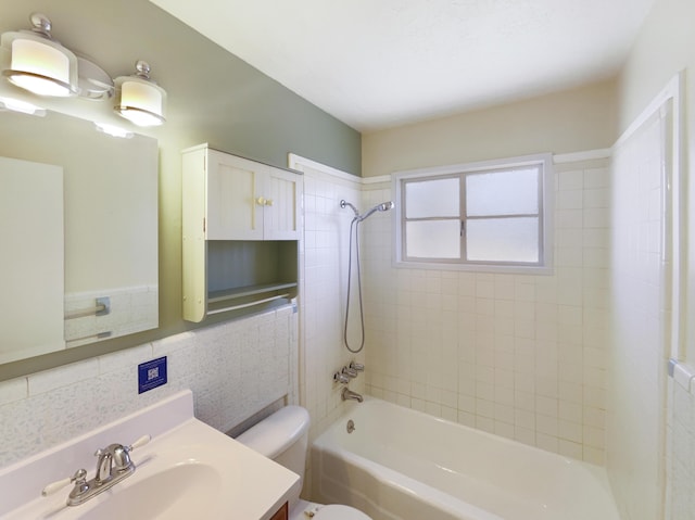 bathroom featuring tub / shower combination, vanity, toilet, and tile walls