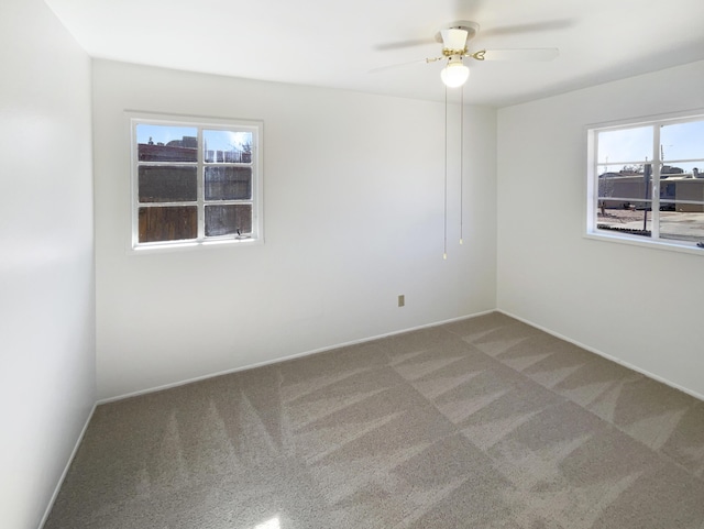 empty room with carpet floors, baseboards, and a ceiling fan