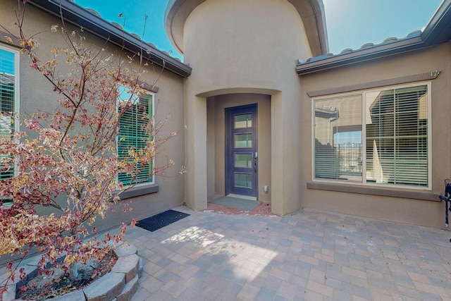 property entrance featuring stucco siding and a patio