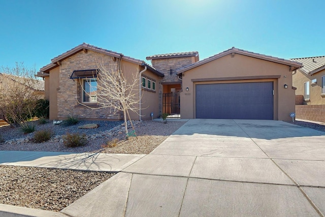 mediterranean / spanish home featuring fence, stucco siding, concrete driveway, a garage, and stone siding