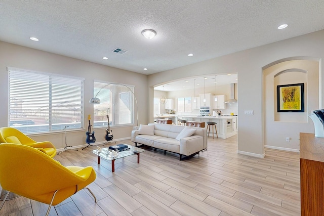 living room with light wood-style flooring, recessed lighting, arched walkways, and baseboards