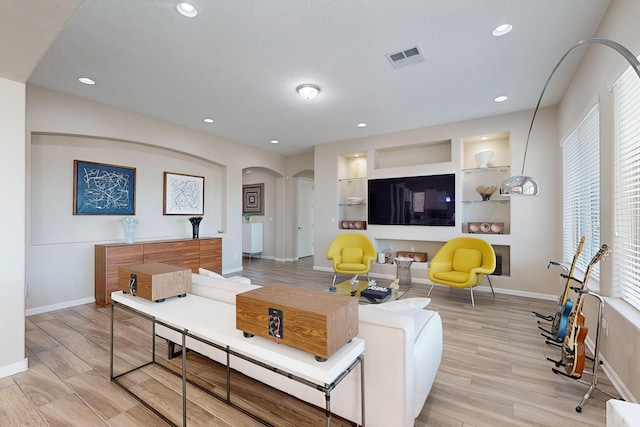 living room featuring recessed lighting, arched walkways, light wood finished floors, and baseboards