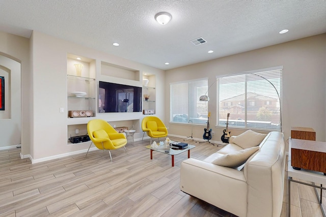 living room with wood finished floors, baseboards, visible vents, recessed lighting, and a textured ceiling