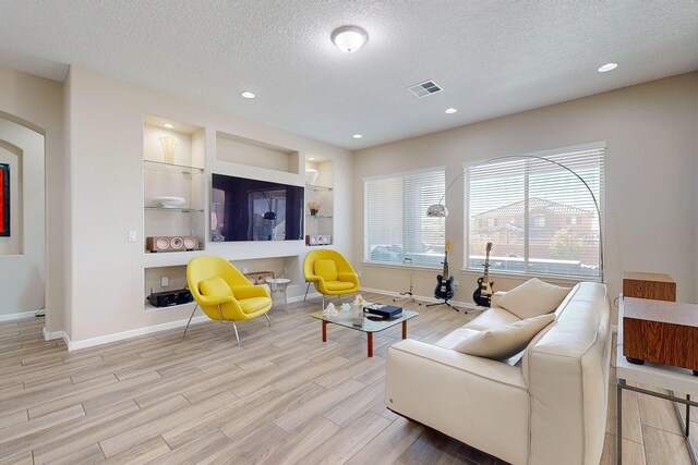 9020 Retablo Rd NW, Albuquerque, NM 87120 - living area with visible vents, baseboards, a textured ceiling, and wood finished floors