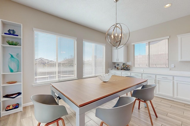 dining space featuring baseboards, recessed lighting, light wood-style floors, a notable chandelier, and a textured ceiling